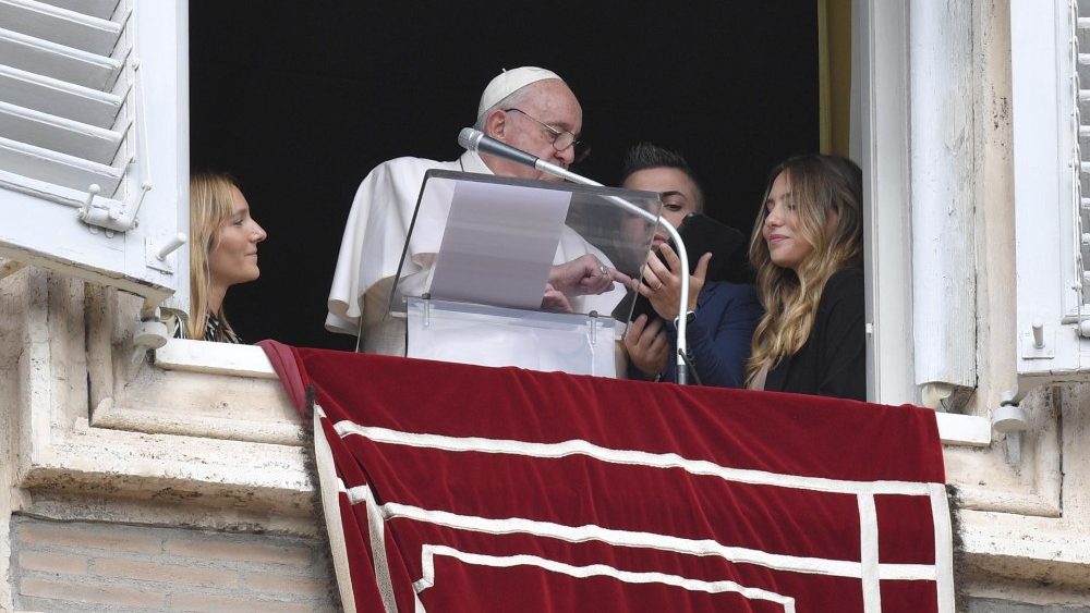 Il Papa accompagnato da alcuni giovani mentre con un tablet si iscrive alla GmG 2023